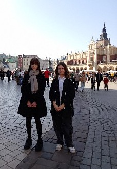 Dwie uczennice stojące na rynku w Krakowie, w tle sukiennice