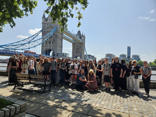 Grupa młodych ludzi stoi na świeżym powietrzu, w tle most London Bridge